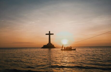 photo of cross in an ocean during dawn