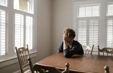 photo of man leaning on wooden table